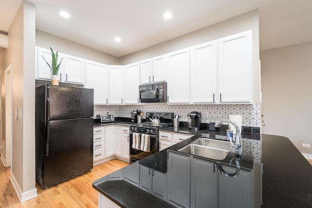 kitchen with tasteful backsplash, black appliances, light wood-style floors, and a sink