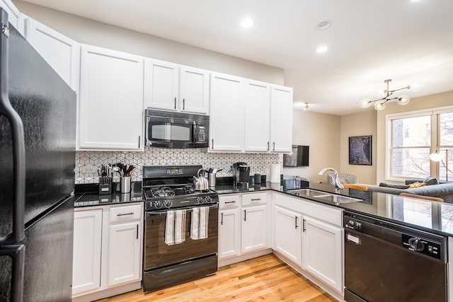 kitchen featuring decorative backsplash, black appliances, light wood-type flooring, and a sink