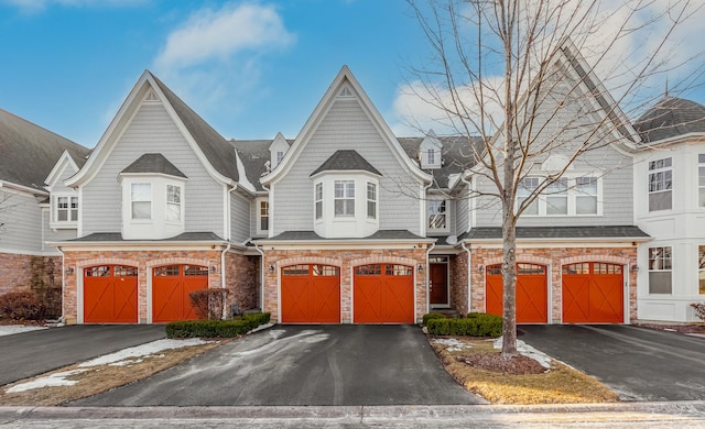 townhome / multi-family property featuring driveway, stone siding, and an attached garage