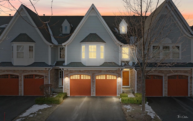 view of front facade featuring driveway, stone siding, and an attached garage