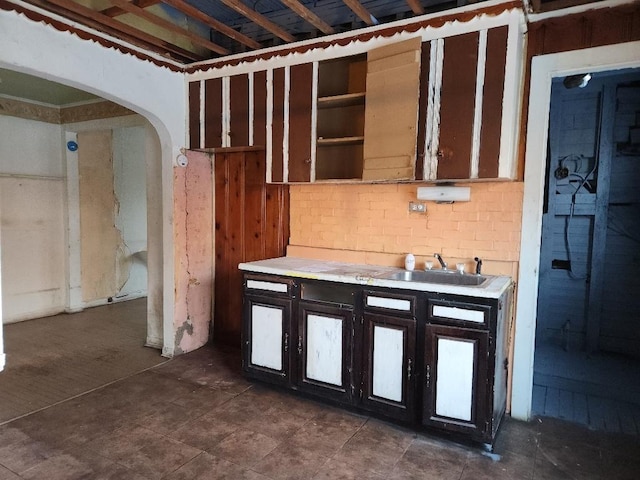 kitchen featuring arched walkways, light countertops, and a sink