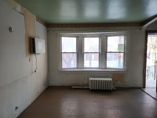 spare room with brick floor, arched walkways, radiator, and a wall mounted AC