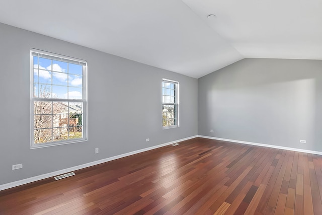 interior space with dark wood-type flooring, lofted ceiling, visible vents, and baseboards