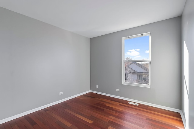 spare room with baseboards, visible vents, and dark wood-type flooring