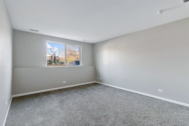 unfurnished room featuring visible vents, dark carpet, and baseboards