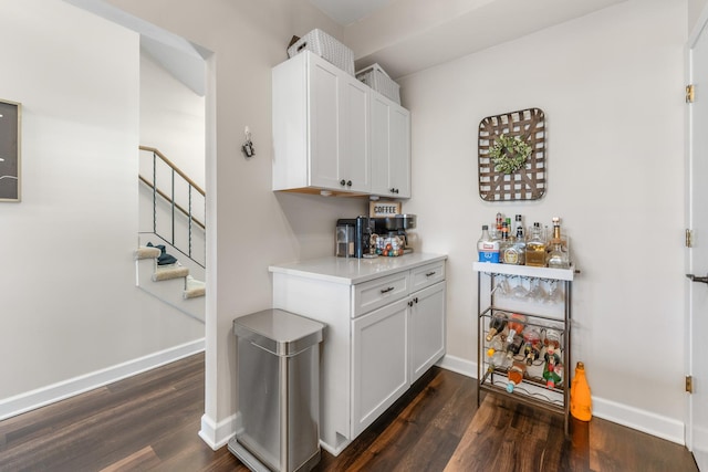 bar featuring stairway, dark wood-type flooring, and baseboards