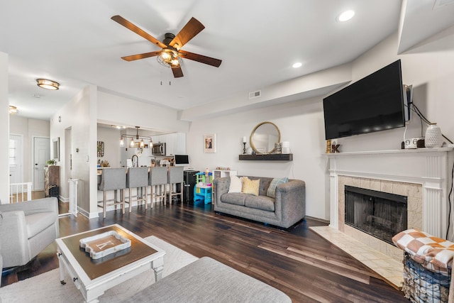 living area featuring visible vents, a ceiling fan, wood finished floors, recessed lighting, and a tile fireplace