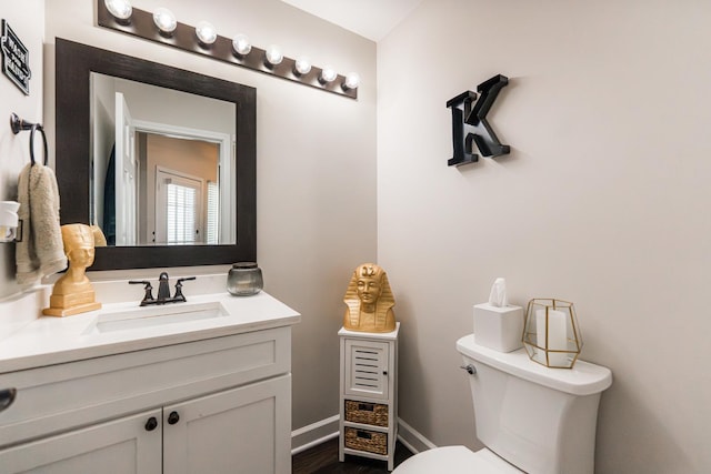 half bath featuring toilet, vanity, and baseboards