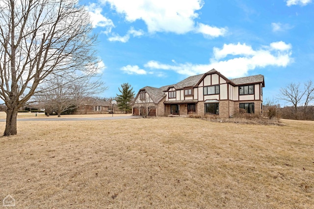 back of house with stucco siding, a lawn, and brick siding