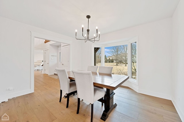 dining area featuring a chandelier, baseboards, and light wood-style floors