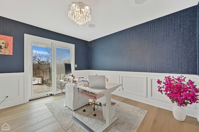 home office featuring wainscoting, a notable chandelier, light wood-style flooring, and wallpapered walls