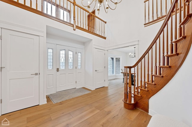 foyer entrance with wood finished floors, a high ceiling, a chandelier, and stairs