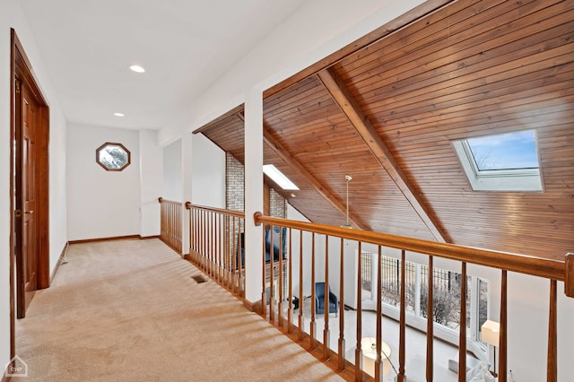 hallway featuring baseboards, visible vents, carpet floors, wood ceiling, and lofted ceiling with skylight