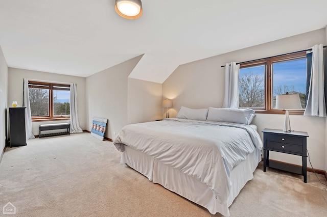 bedroom featuring lofted ceiling, light colored carpet, and baseboards