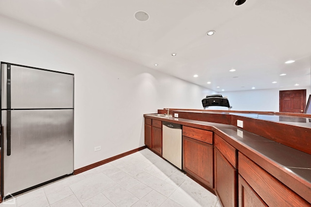 kitchen featuring a sink, dark countertops, recessed lighting, appliances with stainless steel finishes, and brown cabinetry