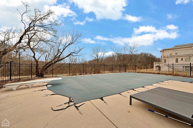 view of swimming pool with a patio area, a fenced in pool, a diving board, and fence