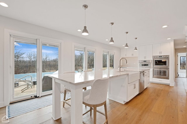 kitchen with white cabinetry, light wood finished floors, and appliances with stainless steel finishes