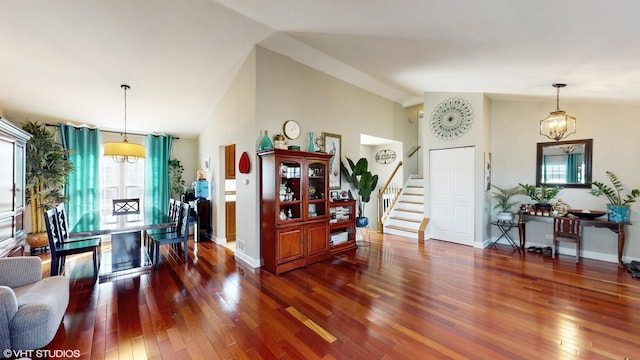 foyer featuring high vaulted ceiling, hardwood / wood-style flooring, baseboards, stairway, and an inviting chandelier