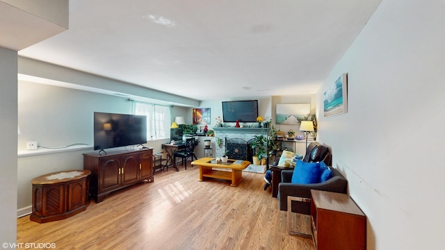 living room with a fireplace with raised hearth and wood finished floors