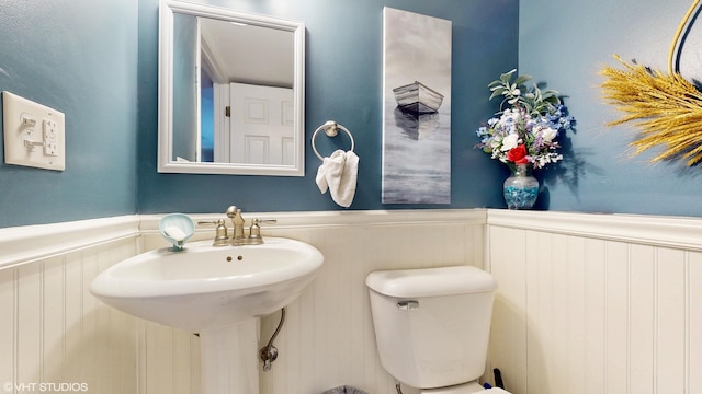 half bath featuring wainscoting, a sink, and toilet