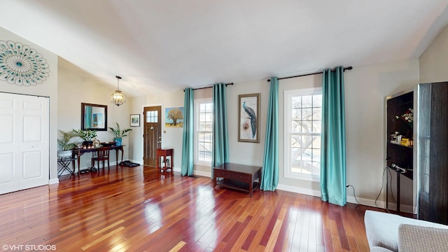 interior space featuring an inviting chandelier, vaulted ceiling, baseboards, and hardwood / wood-style flooring