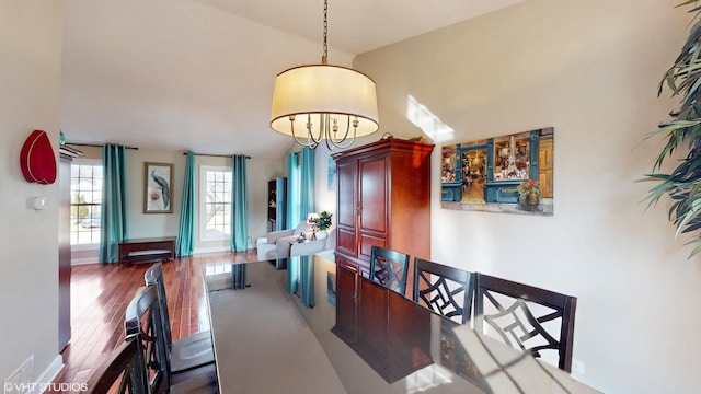 dining space featuring a high ceiling, baseboards, and wood finished floors