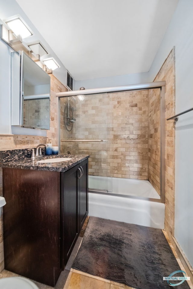 bathroom with visible vents, combined bath / shower with glass door, and vanity