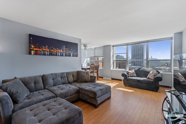 living room featuring baseboards, light wood-style flooring, and a ceiling fan