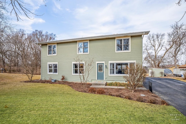 colonial home with a front lawn and aphalt driveway