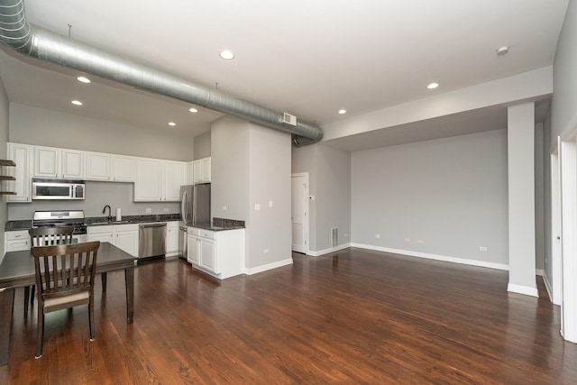 kitchen featuring baseboards, white cabinets, dark wood-style flooring, stainless steel appliances, and a sink