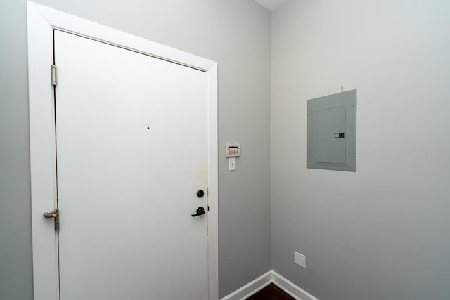 doorway with electric panel and baseboards