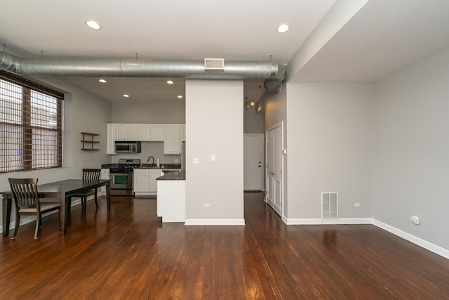 kitchen featuring appliances with stainless steel finishes, dark wood-style flooring, white cabinets, and a sink