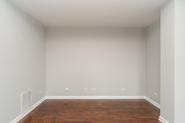 spare room featuring dark wood-style floors, visible vents, and baseboards