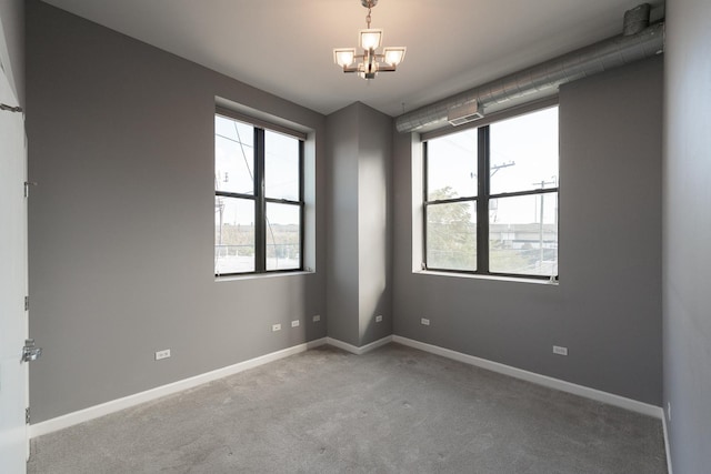 unfurnished room with a chandelier, carpet flooring, and baseboards