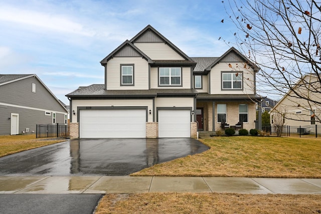 craftsman inspired home with brick siding, an attached garage, fence, driveway, and a front lawn