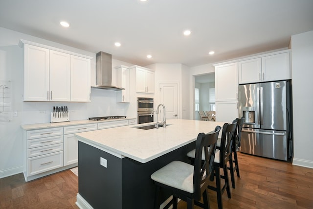 kitchen featuring stainless steel appliances, dark wood-type flooring, a sink, and wall chimney range hood