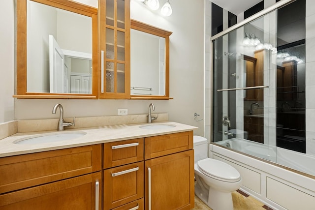 full bath featuring shower / bath combination with glass door, a sink, toilet, and double vanity