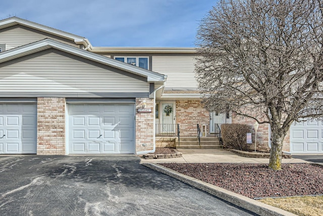 view of front facade featuring driveway, an attached garage, and brick siding