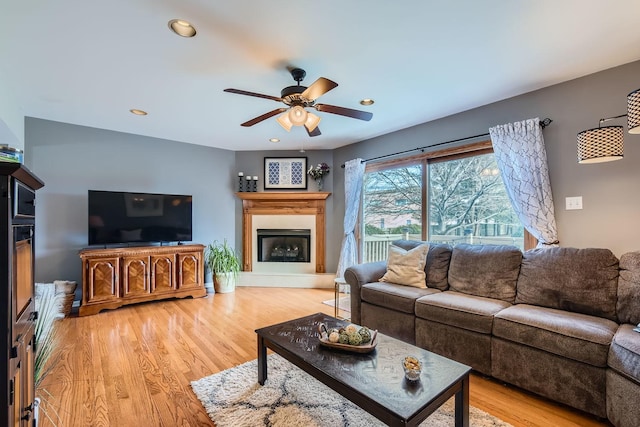 living room with a fireplace with raised hearth, light wood-style flooring, and recessed lighting