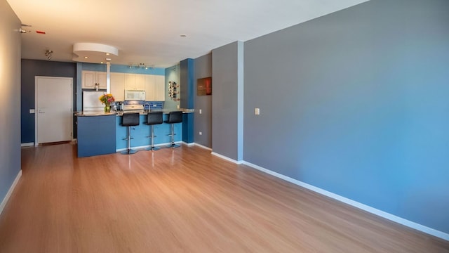 330 N Jefferson St Unit 603, Chicago, IL 60661 - kitchen with white microwave, fridge, a peninsula, a kitchen bar, and wood finished floors