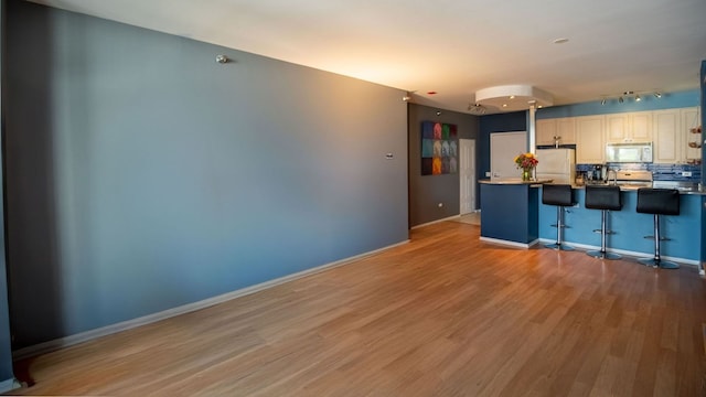 330 N Jefferson St Unit 603, Chicago, IL 60661 - kitchen with white appliances, light wood-style flooring, a kitchen bar, tasteful backsplash, and rail lighting
