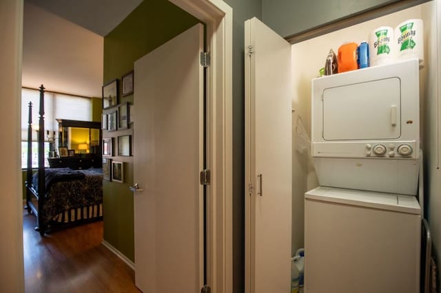 laundry area with wood finished floors, stacked washer and clothes dryer, and laundry area