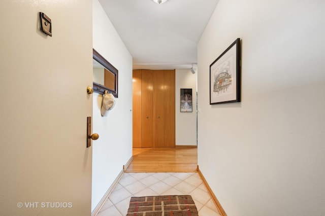 corridor with light tile patterned floors and baseboards