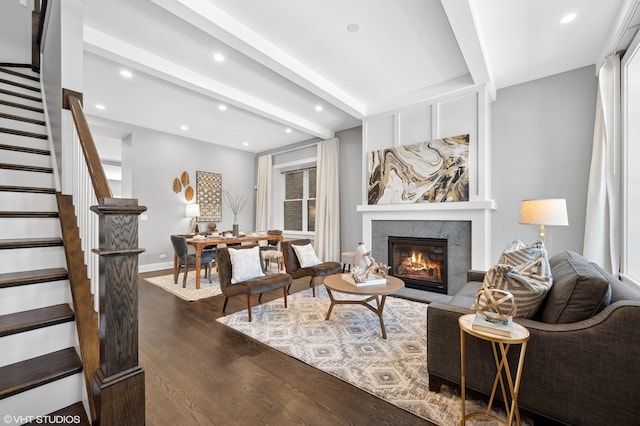 living area featuring beamed ceiling, stairs, a premium fireplace, recessed lighting, and dark wood-style flooring