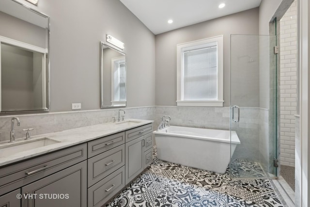 full bathroom with tile patterned floors, a soaking tub, tile walls, and a sink