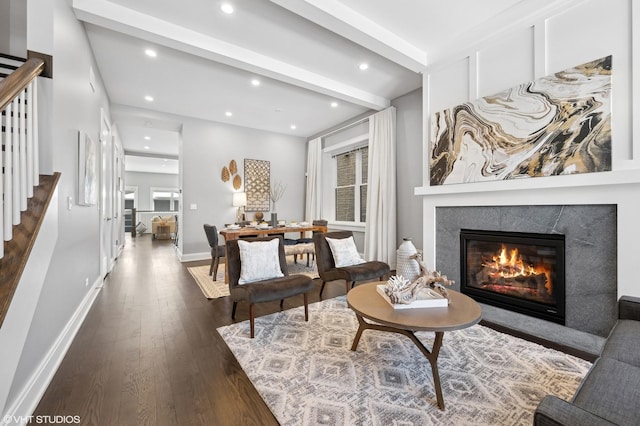 living area with baseboards, dark wood finished floors, stairway, beamed ceiling, and a glass covered fireplace