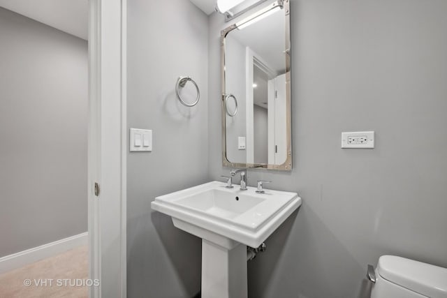 bathroom featuring toilet, baseboards, and a sink