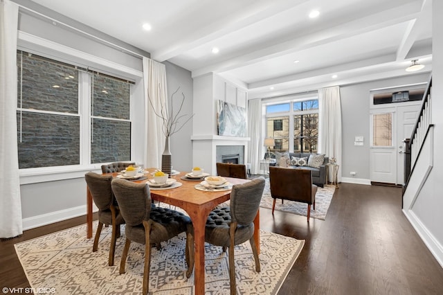 dining space with stairway, dark wood-style floors, baseboards, beam ceiling, and a lit fireplace