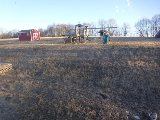 view of yard featuring an outdoor structure, playground community, and a barn