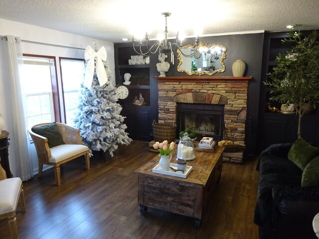 living room featuring built in features, a fireplace, an inviting chandelier, wood finished floors, and a textured ceiling